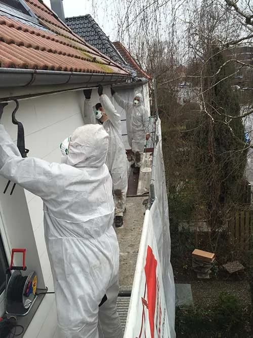 Dachdecker in Schutzkleidung bei Asbestarbeiten